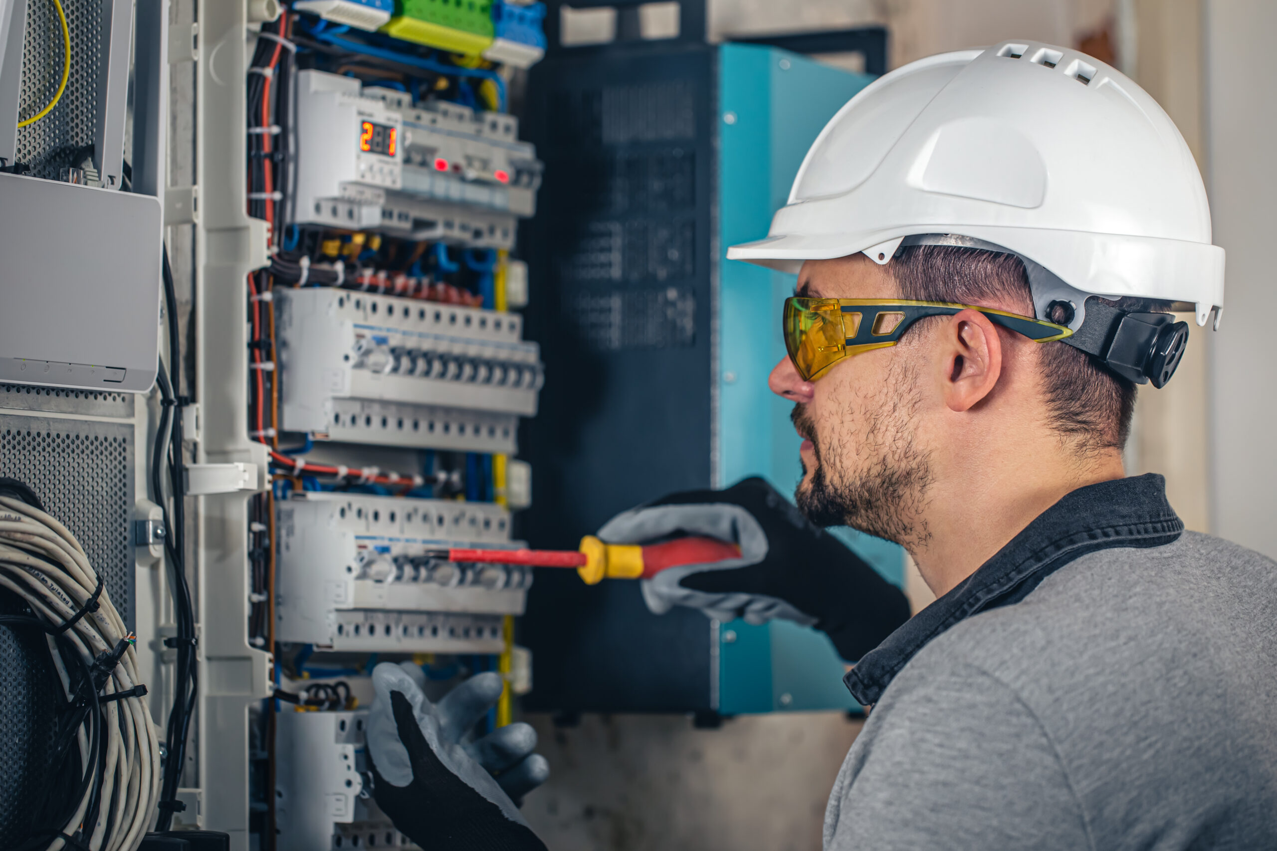 Man, an electrical technician working in a switchboard with fuses.